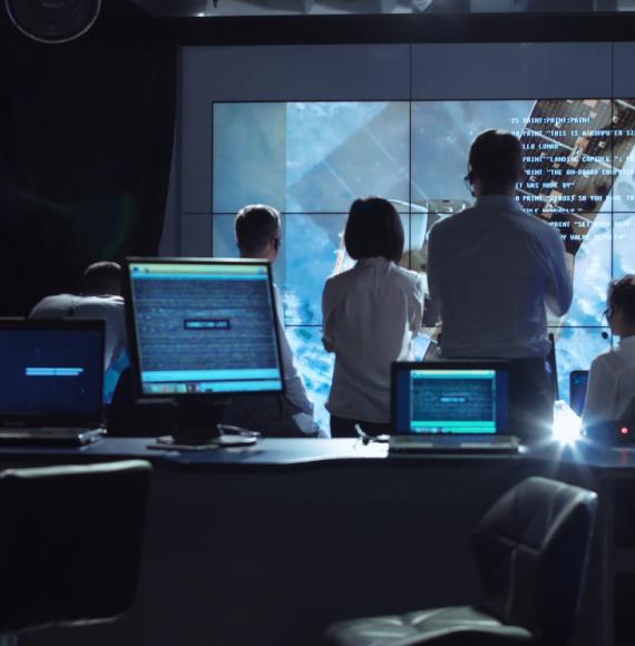 A group of people gather round a big screen whilst working on a digital project