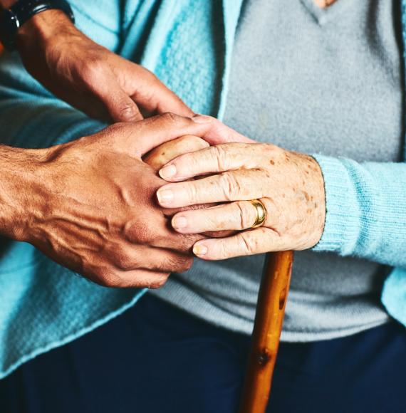 A carer holds hands with an older person