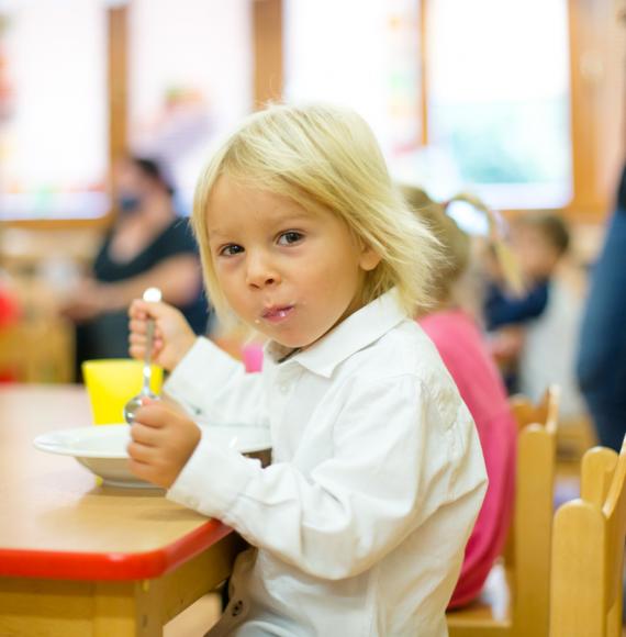 A child sits at school and eats lunch