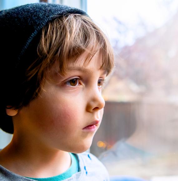 Pensive looking child looks out of a window