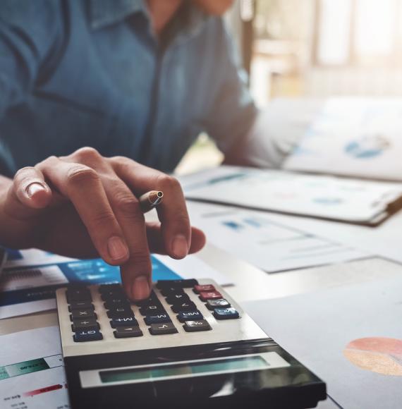 An unidentifiable man working out a budget with a calculator