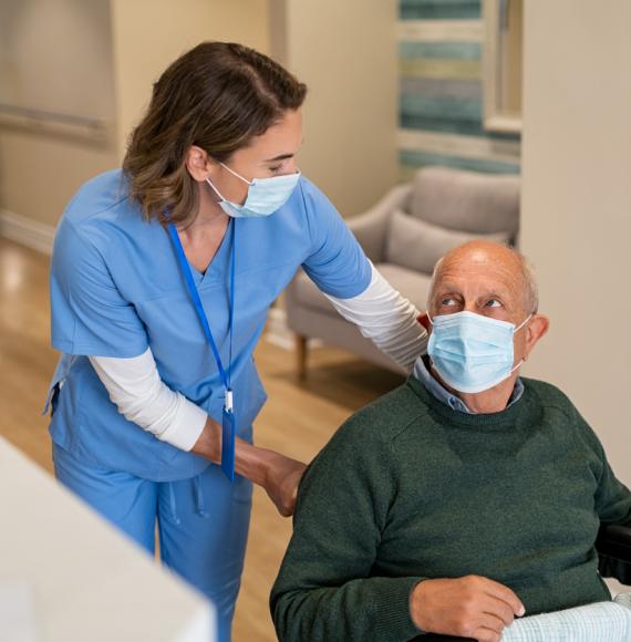 A nurse helping an older male in a wheelchair