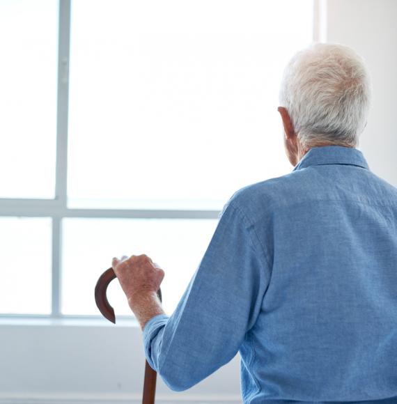 Old man with dementia looks out of a window.