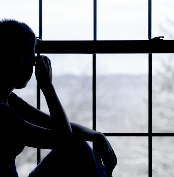 A homeless child looks out of the window of a hostel