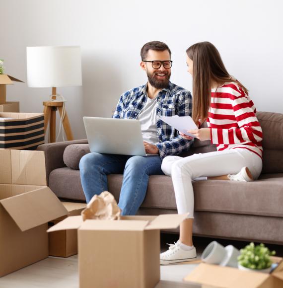 Couple in room full of boxes after moving into their first home