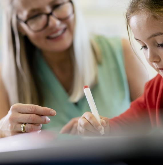 Young girl sat in classroom with her teacher