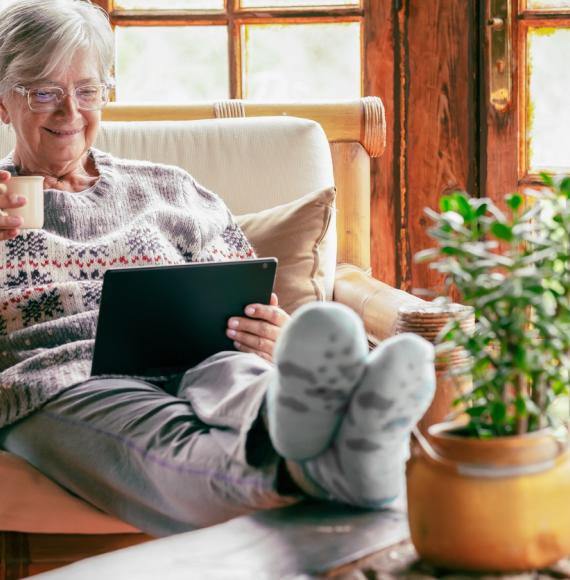 Older lady sat at home using a tablet