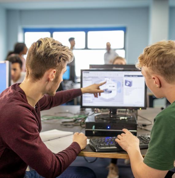 Two young men work together on a project on a computer