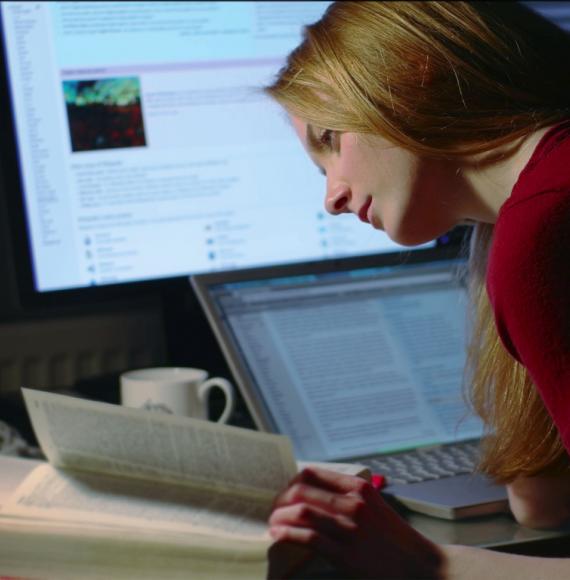 A girl studying/working at a desk with two computers