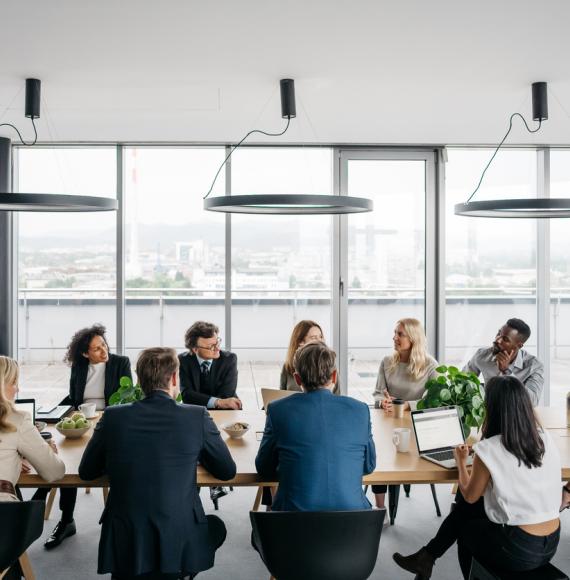 A photo of a business meeting in a modern office with large windows.