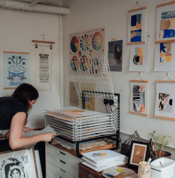 An artist laying prints to dry on a rack