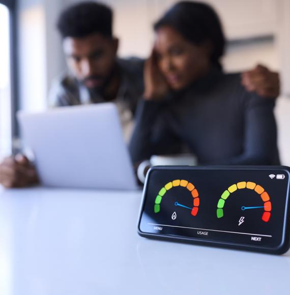 Couple looking anxious at laptop with smart energy meter in the foreground