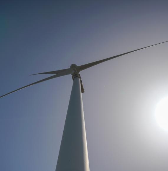 Wind turbine from below, with a blue sky behind it