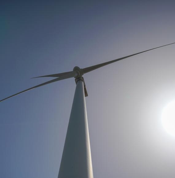 Wind turbine from below, with a blue sky behind it