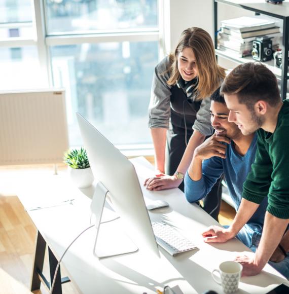 Three young people gathered round a computer