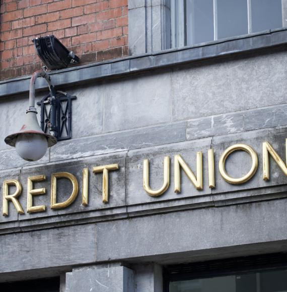 Sign of a credit union in gold writing on a stone wall