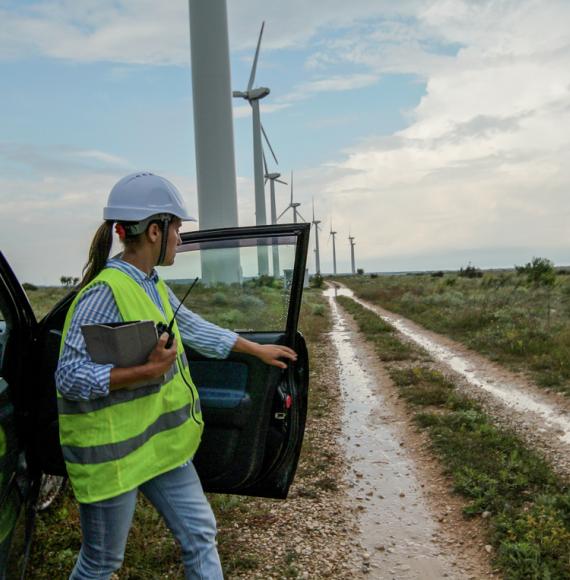 Woman getting out of a car at a group of wind turbines