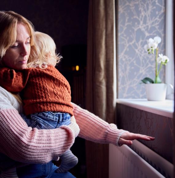 Woman looking out of a window with a child in her arms