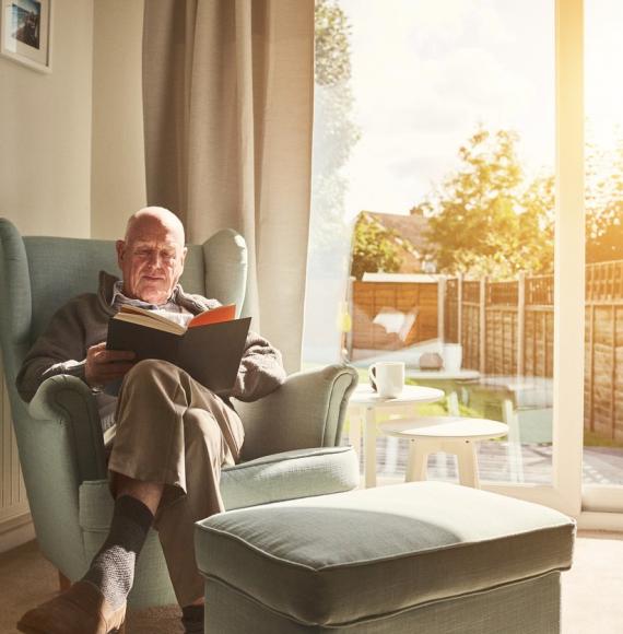 Old man reading in his home