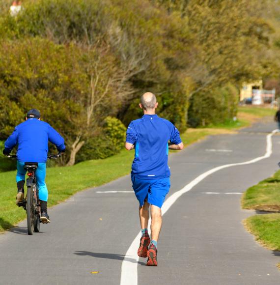 Person jogging behind a cyclist on the Wales National Coastal Path