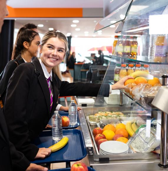 Schoolgirl smiling in the queue for lunch at school