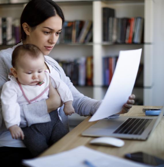 Woman holding baby and looking at a bill