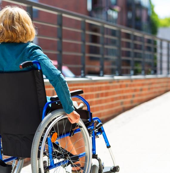 Woman sat in a wheelchair, going up a ramp