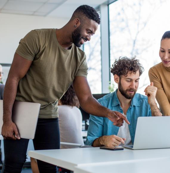 A team of creative professionals looking at the lap top and brainstorming ideas