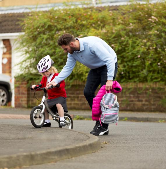 Dad helping his daugher cycle to school