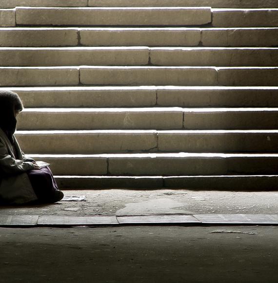 Homeless woman sitting on the floor by some steps