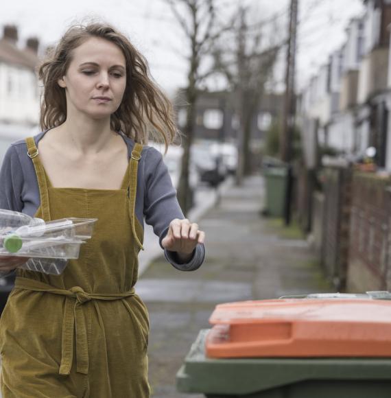 Mid adult British woman recycling plastic containers