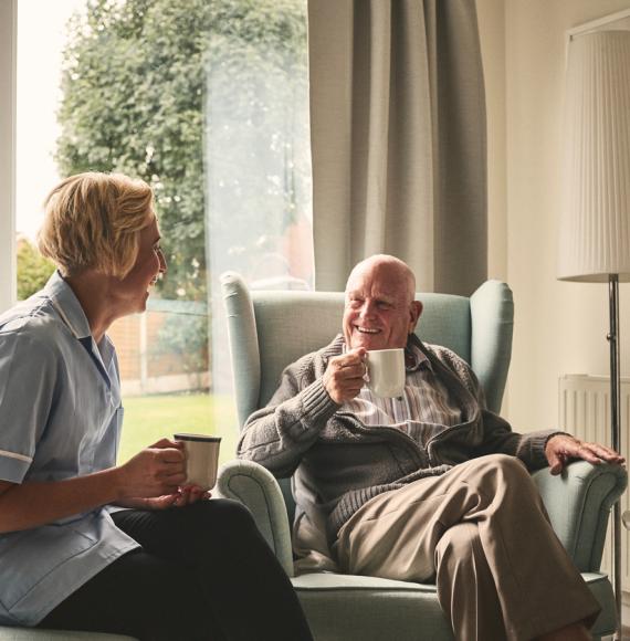 Relaxed senior man and female nurse having coffee