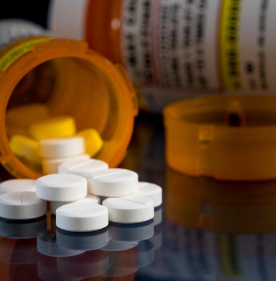 Prescription bottle for Oxycodone tablets and pills on glass table with reflections