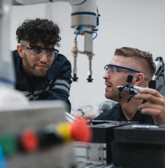 Student engineer Assembling Robotic Arm with computer in Technology Workshop