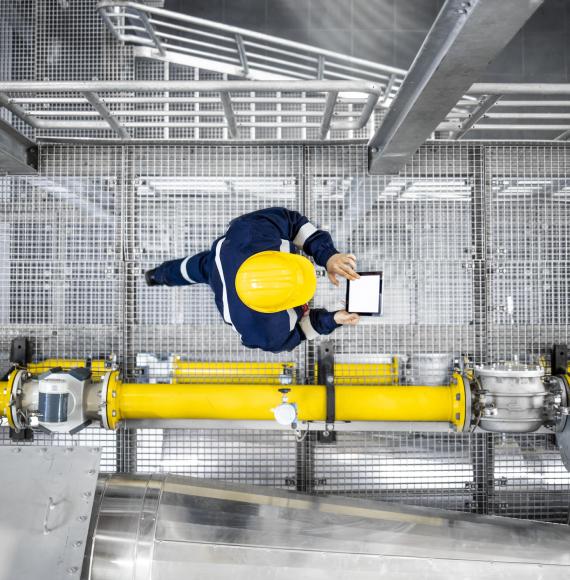 Top view of refinery worker walking by gas pipes