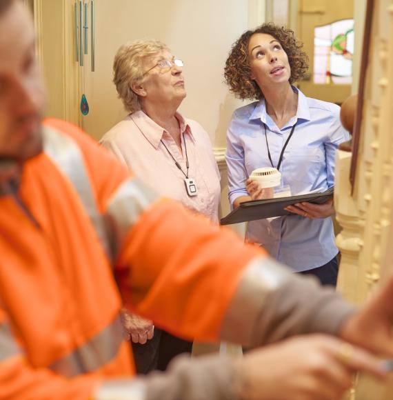 an alarm fitter fits an alarm in a senior woman's house