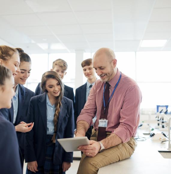 A male teacher talking to a group of students in a science room