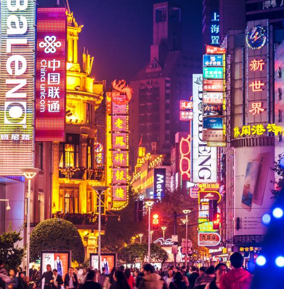 Crowds walk below neon signs on Nanjing Road, Shanghai