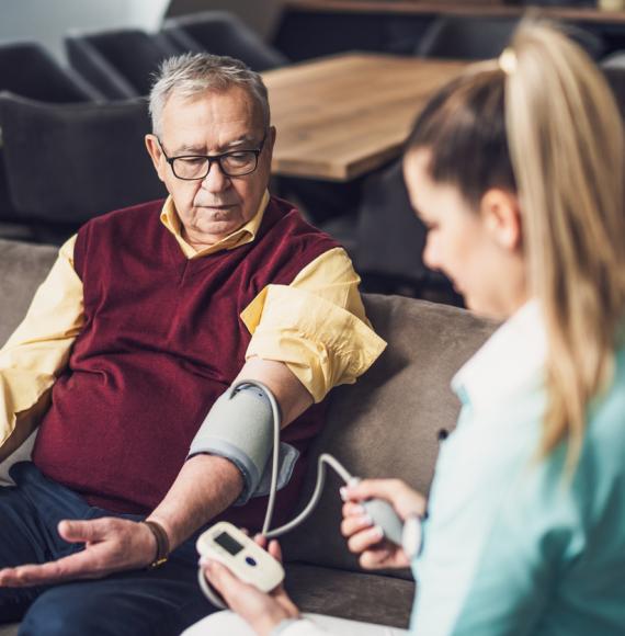 Home doctor is measuring blood pressure of old man at his home