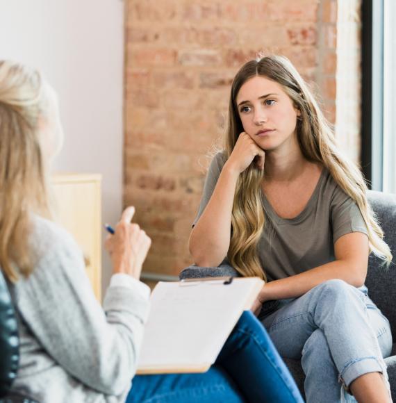 Teen girl listens to advice from unrecognizable female therapist