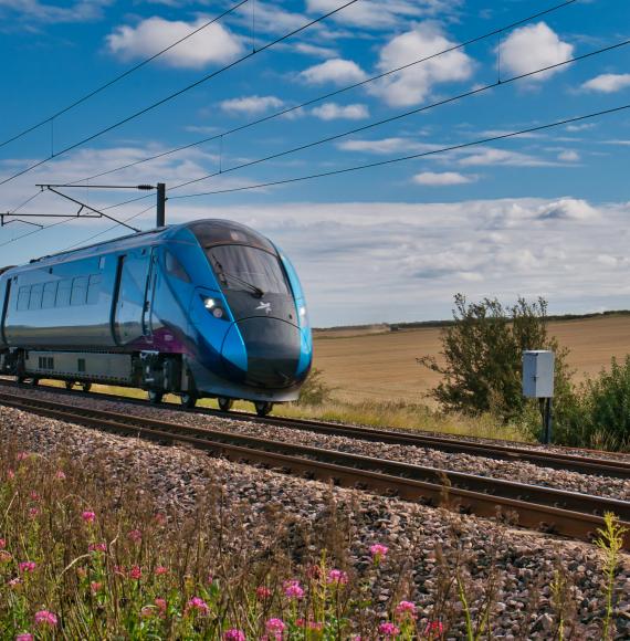 Transpennine Express train travelling at speed in Northumberland, UK - taken on a sunny day with white clouds.