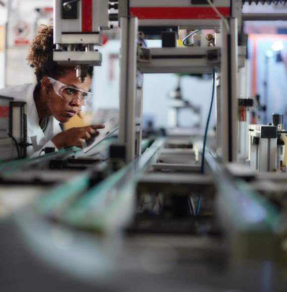 Young scientist using touchpad while working on machinery in a lab