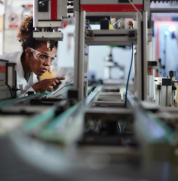 Young scientist using touchpad while working on machinery in a lab