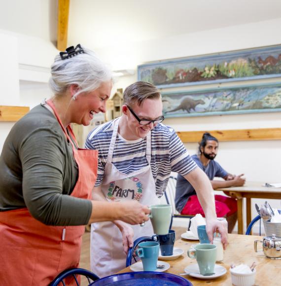 A man and woman prepare hot drinks in the local farm cafe.