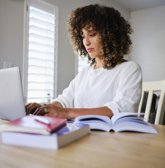 A young woman studying with a laptop computer in a home.