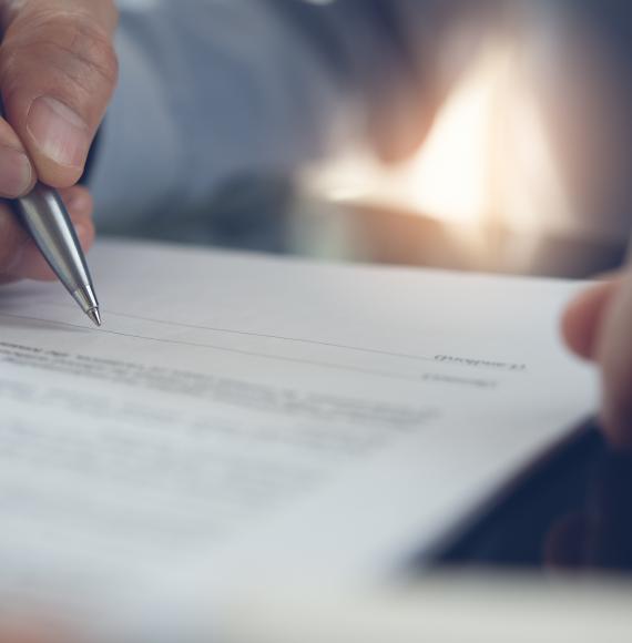 Businessman with pen in hand reading official business contract