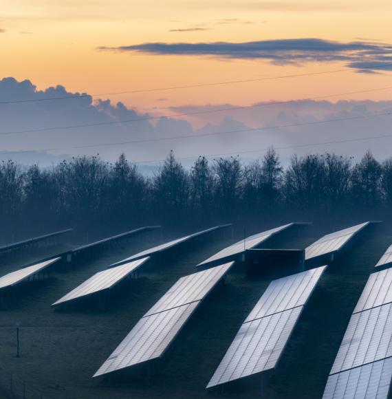 Solar energy park and conventional electricity pylon at sunset, Hampshire, England