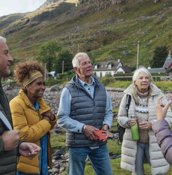 a small group of adults standing on the shore of a sea loch in Torridon, Scotland