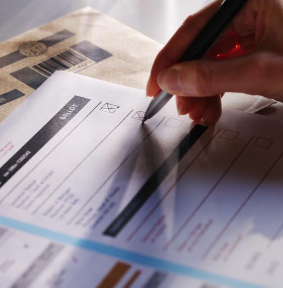 a woman’s hand filling in a postal ballot  voting form.