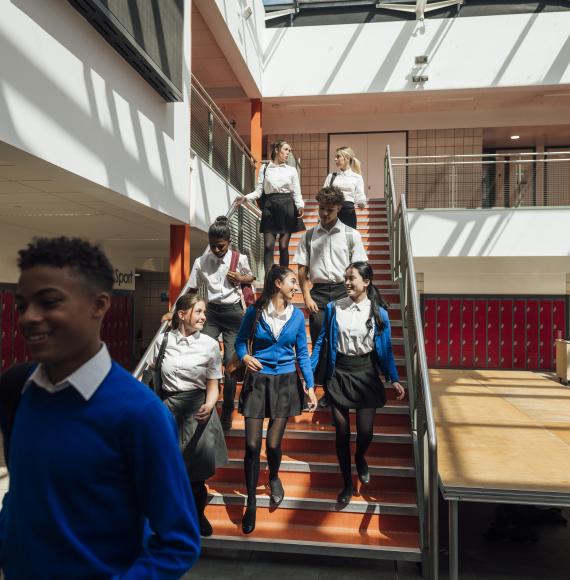 A wide angle view of a group of high school students who are rushing to their next class